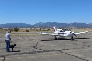 Foster a dog, puppy foster coodinator Mary Luton with puppy Iris onthe tarmac meeting adopters as they taxi their small plane ver