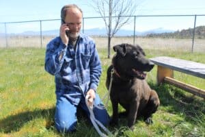 Loving homes, Manager Rick Formanek kneeling taking phone call with Penguin sitting relaxed