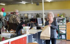 Thrift Store volunteer staff bagging puchases for customerfor