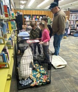 Children standing visiting with puppy